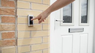 Person pressing electric doorbell outside modern uPVC front door