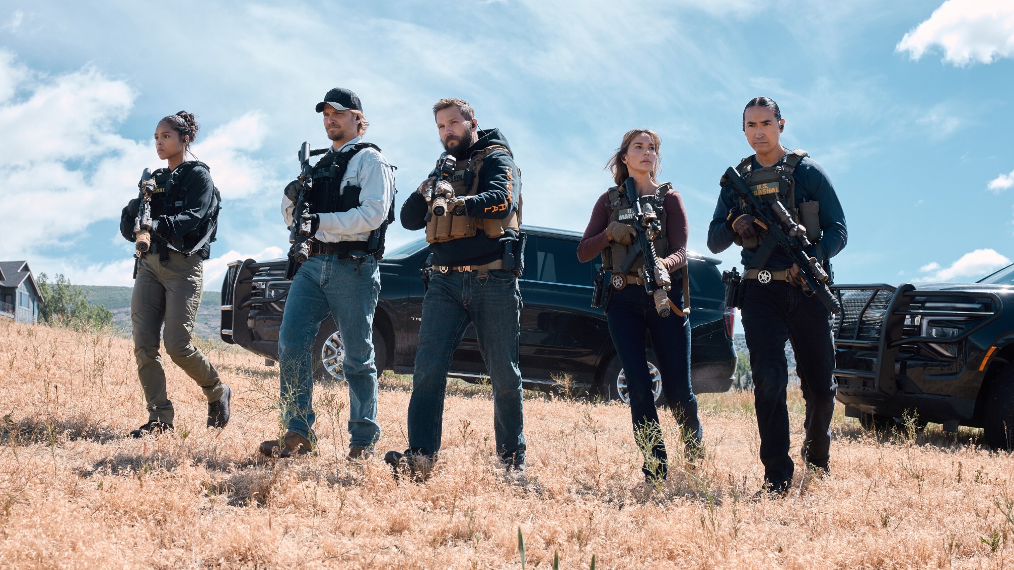 (L-R): Ash Santos as Andrea Cruz, Luke Grimes as Kayce Dutton, Logan Marshall-Green as Pete Calvin, Arielle Kebbel as Belle, and Tatanka Means as Miles Kittle. They're all holding guns. 