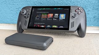 Xbox Ally X leaning against a blue wall with a power bank in front of it. 