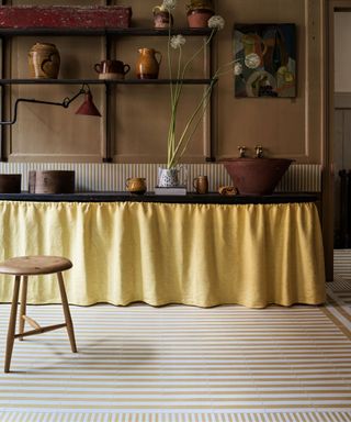 striped tile flooring with a yellow cupboard skirt and utility sink