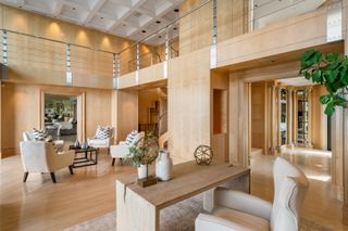 An open plan living area with wood panelled walls, arm chairs, and a desk space