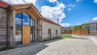 barn conversion with large driveway and fence and dwarf wall