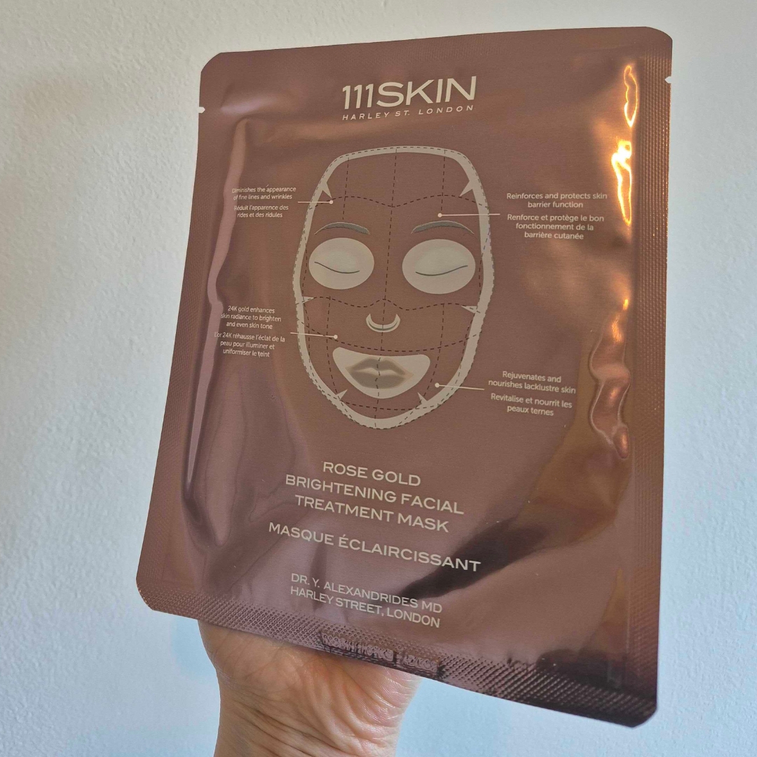 A close-up of Digital Beauty Writer, Naomi Jamieson holding the 111SKIN Rose Gold Brightening Facial Treatment Mask, in front of a cream wall