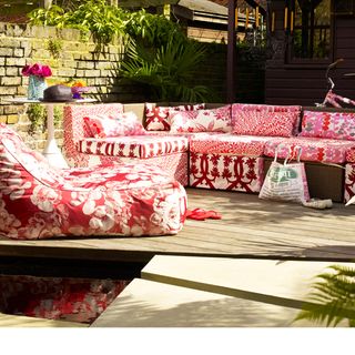 red patterned garden seating on decking with circular table