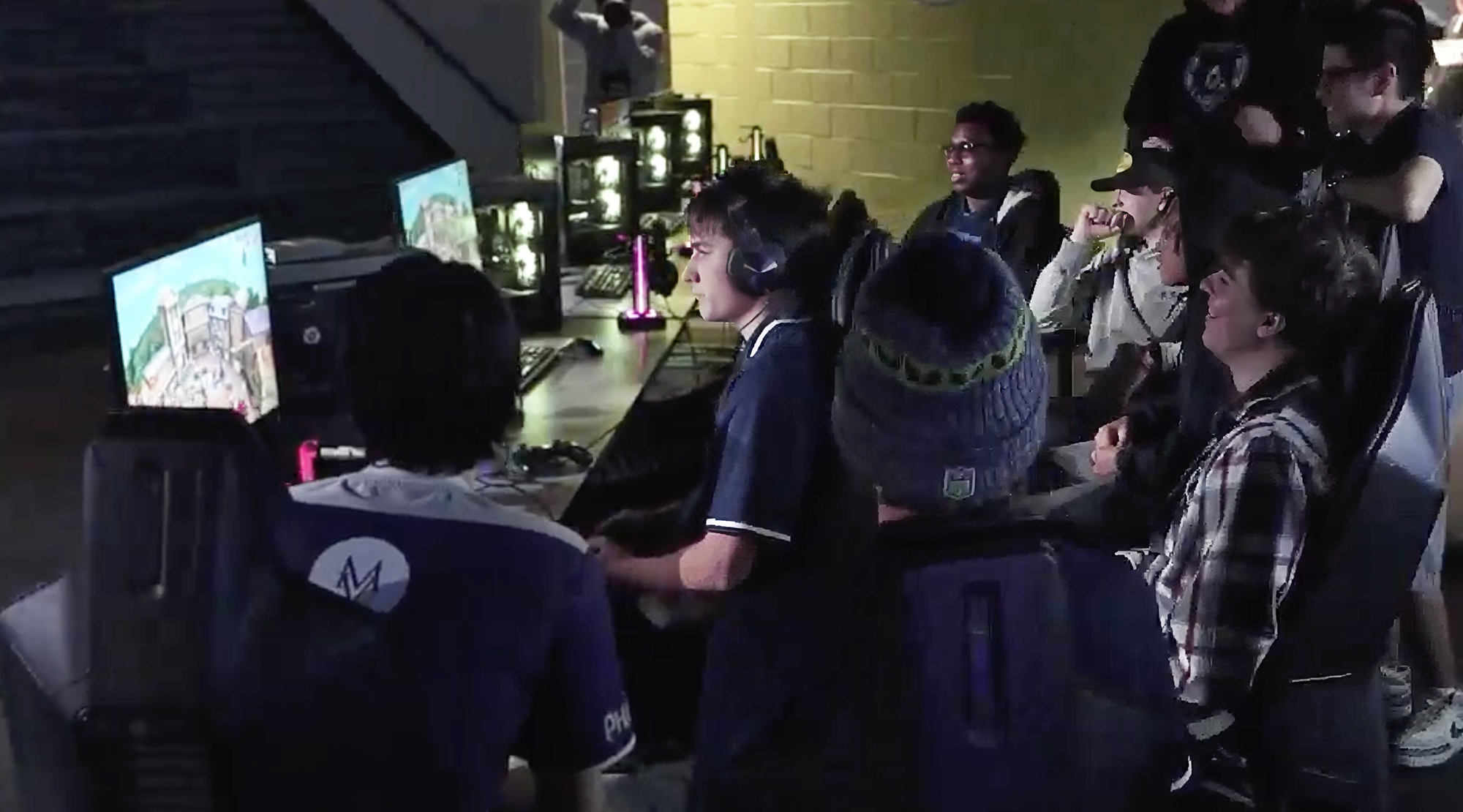 Gamers playing esports as a crowd looks on.