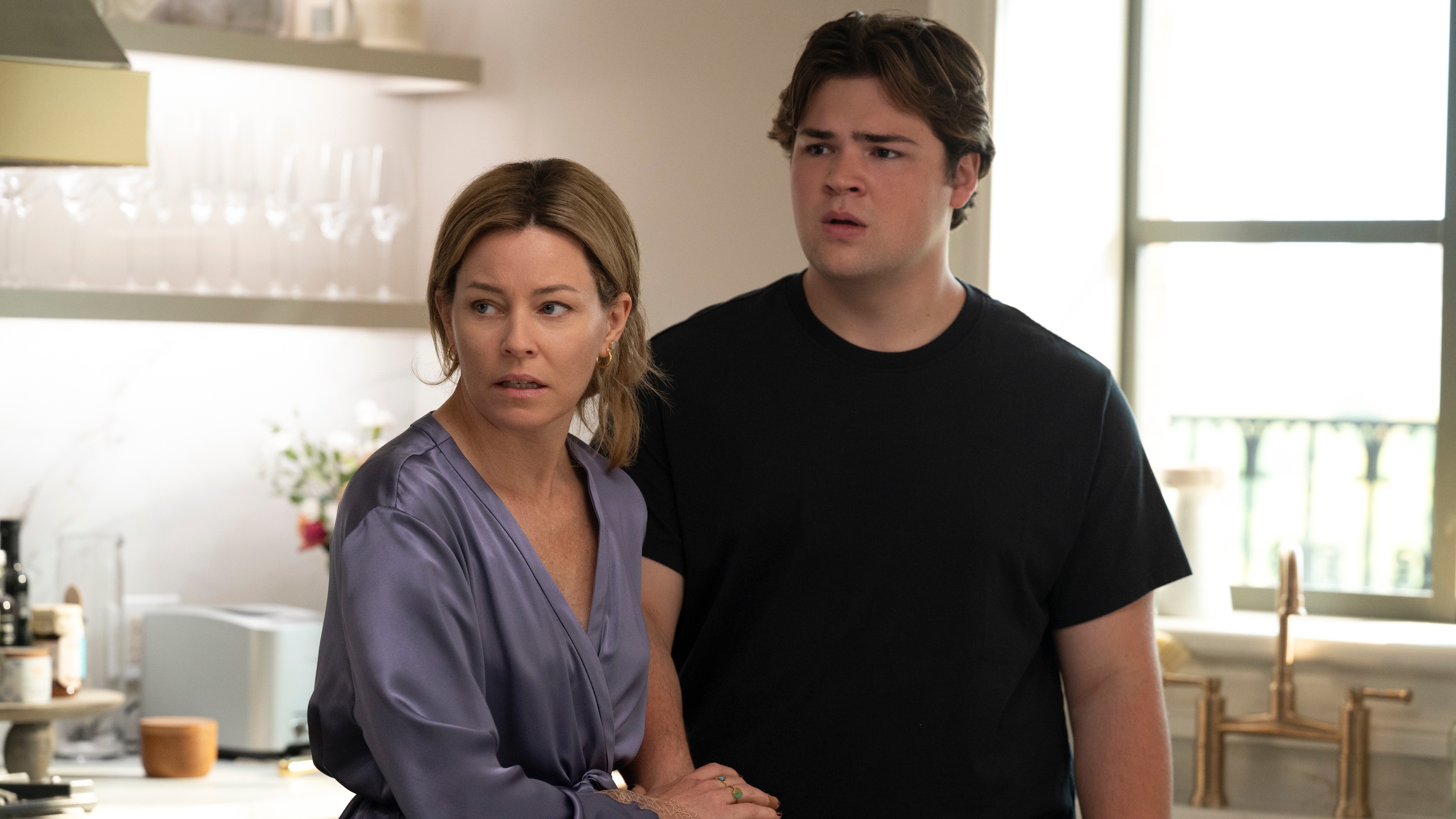 Nicky and Ethan looking shocked as they stand in a fancy kitchen