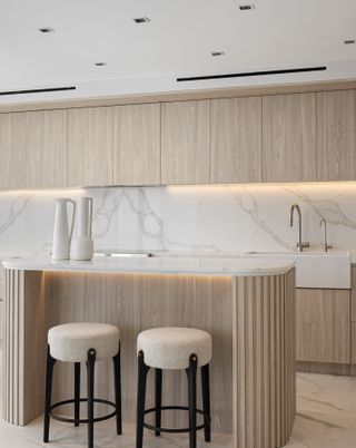 A kitchen in all white and wood with undercabinet lighting