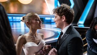 Slater and Grande holding hands and smiling at the Oscars