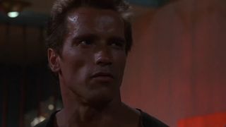 Arnold Schwarzenegger stands in a hotel room in Commando