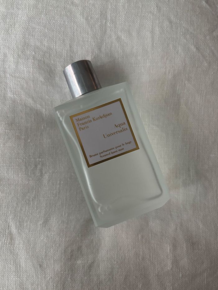 A Maison Francis Kurkdjian room spray on a white linen background