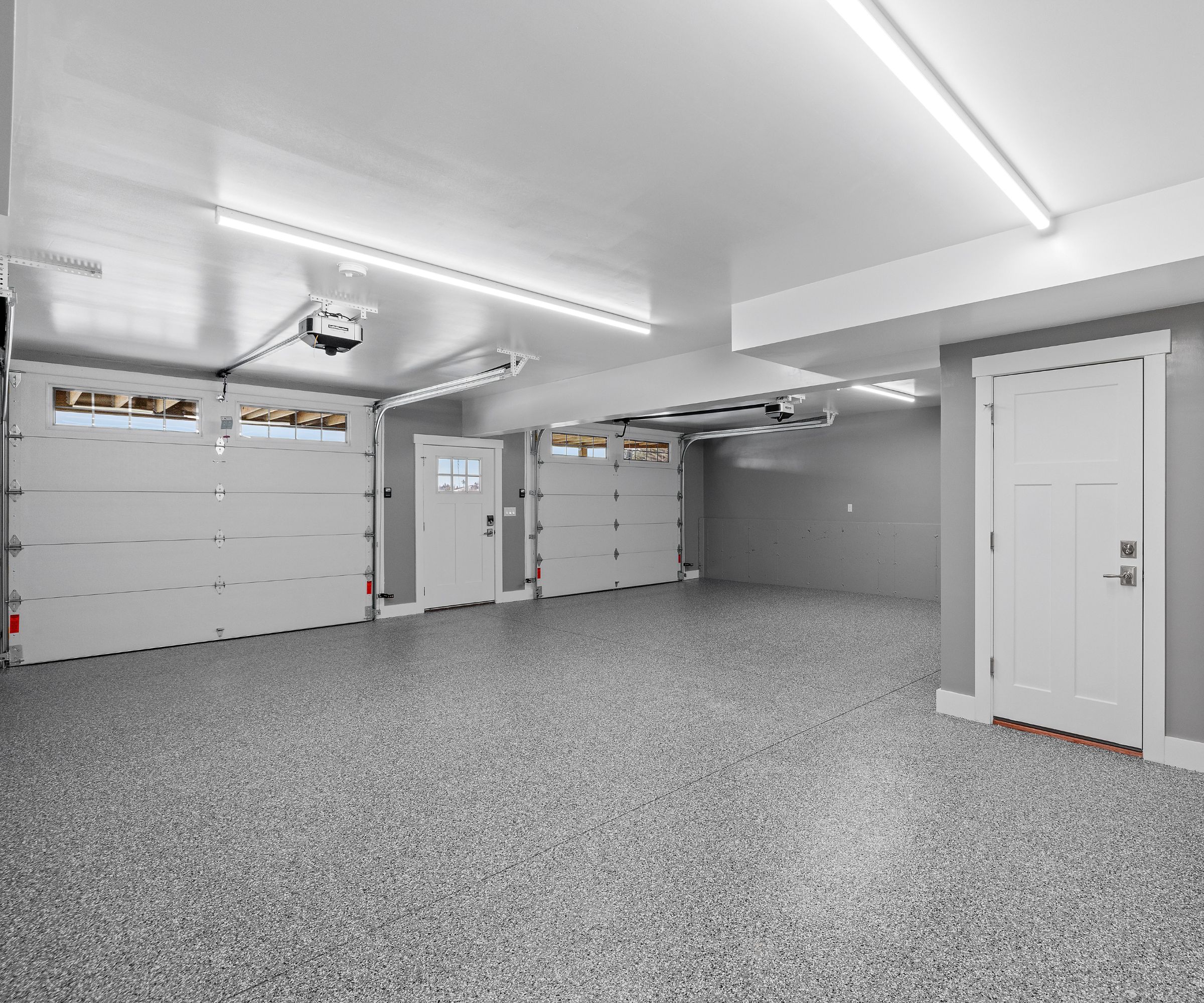 An interior view of an empty garage with a metallic surface floor and lighting