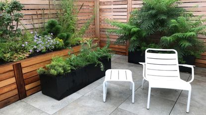 White metal slatted chair and matching table plus black and wooden planters 