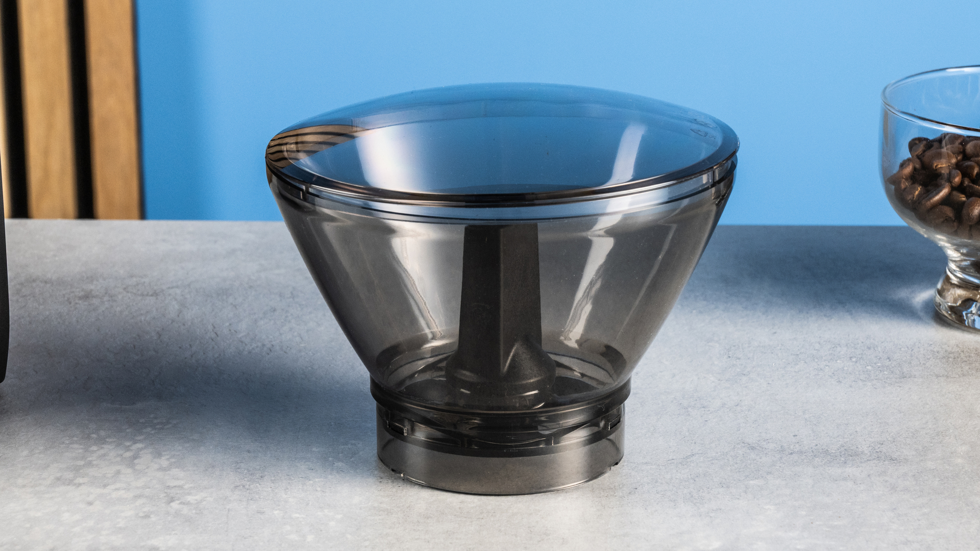 the baratza encore esp pro coffee grinder photographed against a blue tom's guide background with a bag of coffee to the side and showing the grinder in action