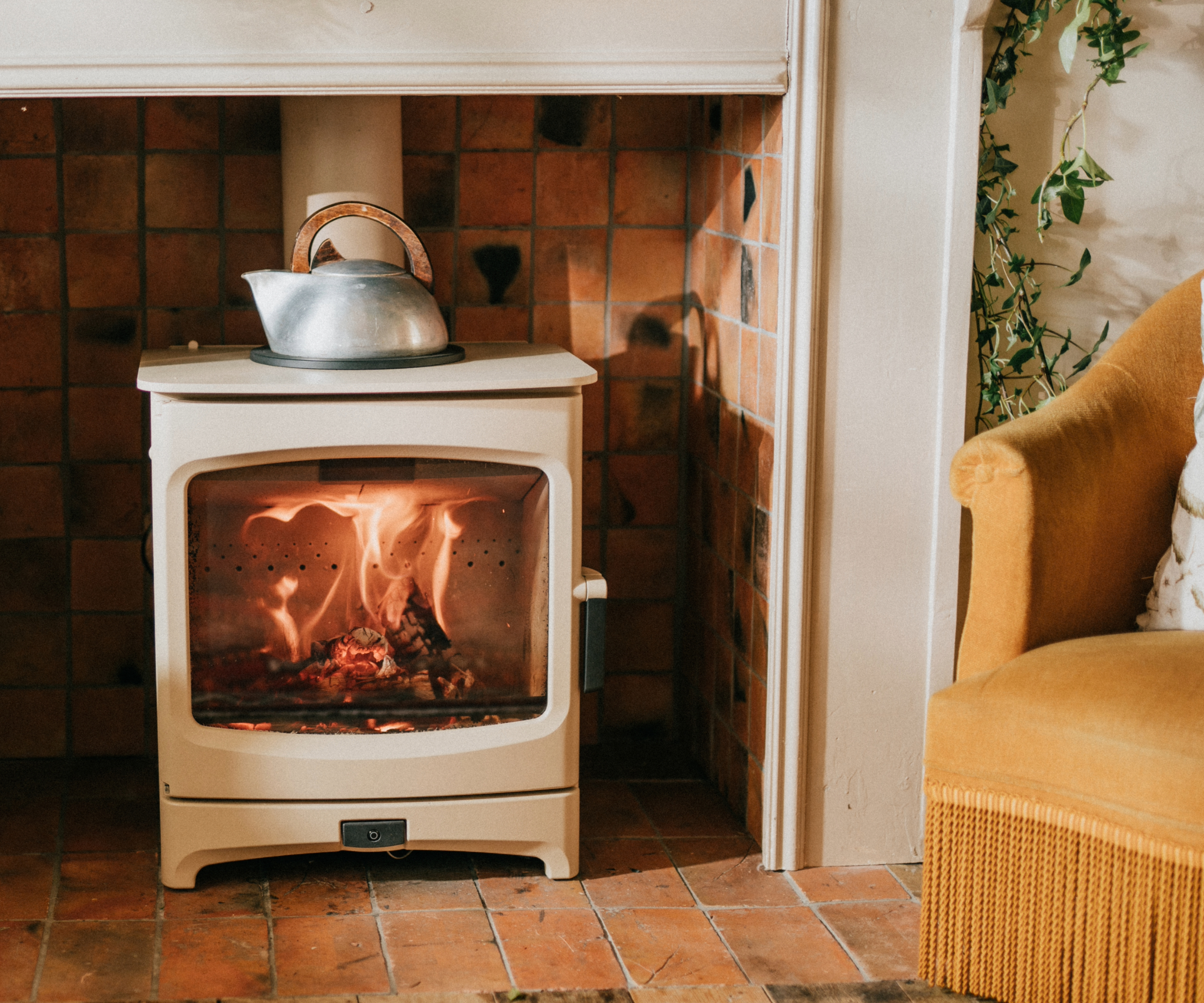 A white log burner with flames forming a heart inside and a kettle on top