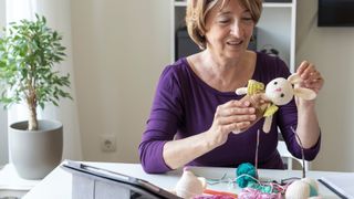 A lady crochets a stuffed toy