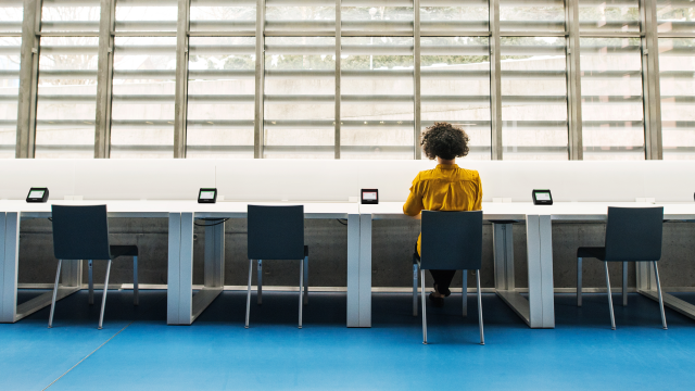 New Crestron desk scheduling devices in an office with only one woman using a desk.