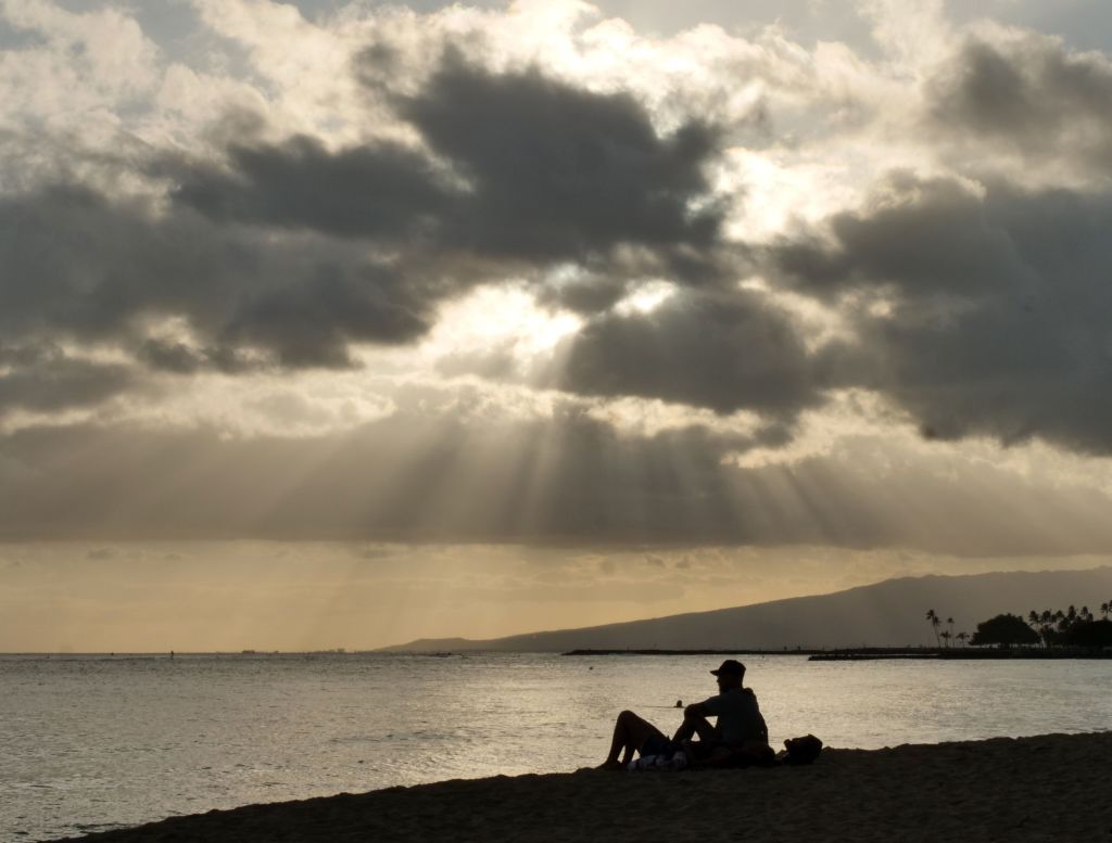 People sit on Waikiki Beach as Hurricane Douglas approaches.