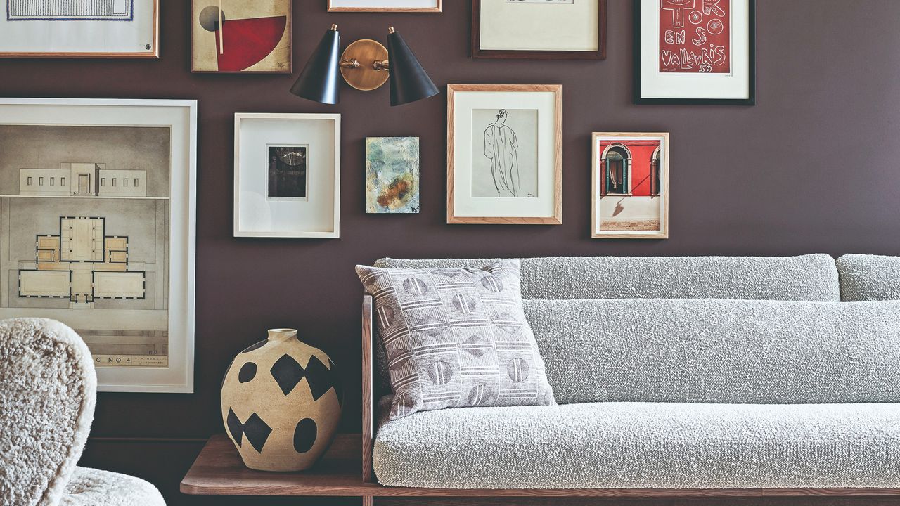 A living room with a dark purple gallery wall