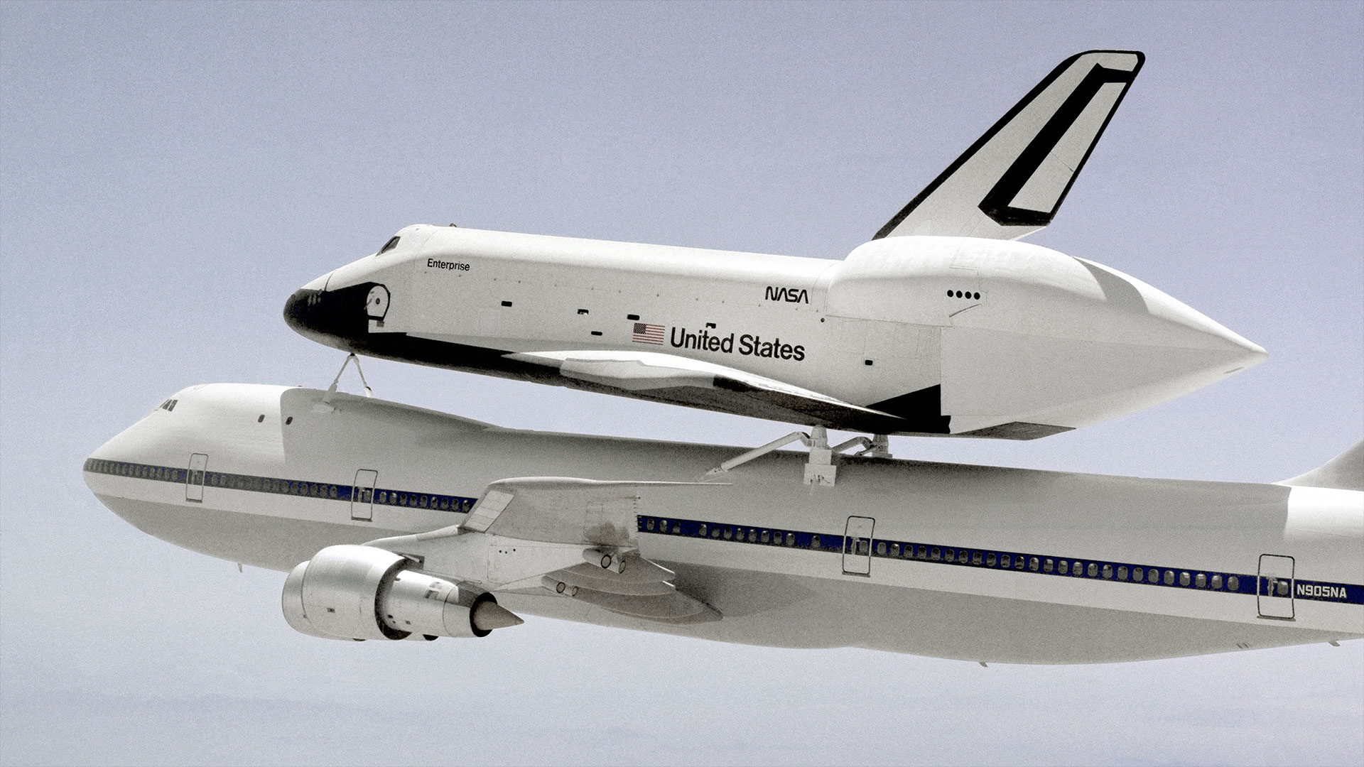 a jumbo jet carries a winged spacecraft atop its back while in flight.