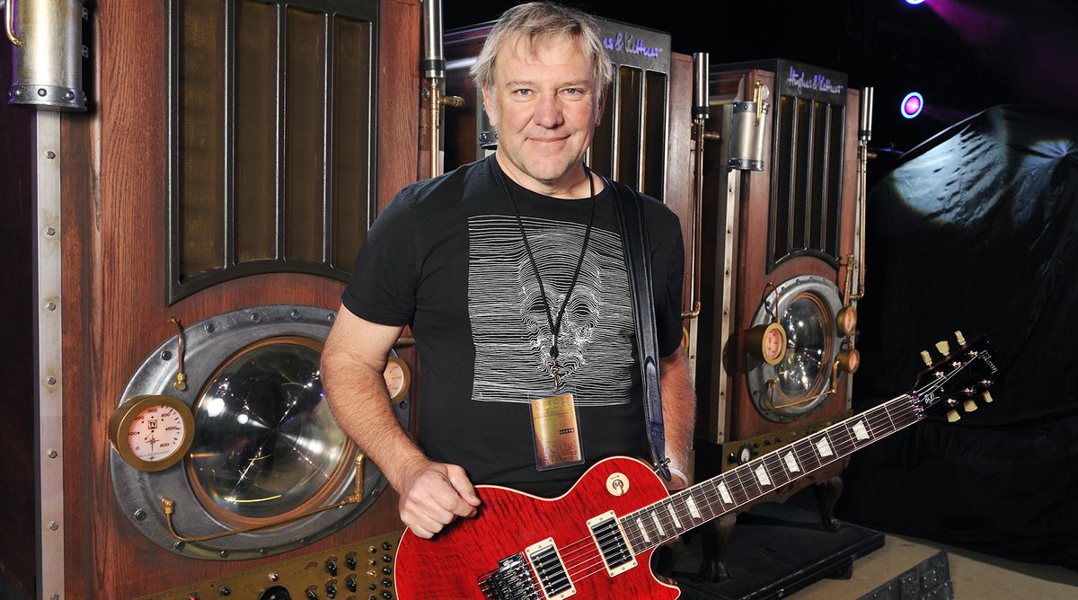 Alex Lifeson stands backstage with a red Gibson Les Paul guitar 