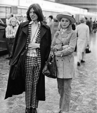 black and white image of mick jones and marianne faithful standing in an airport