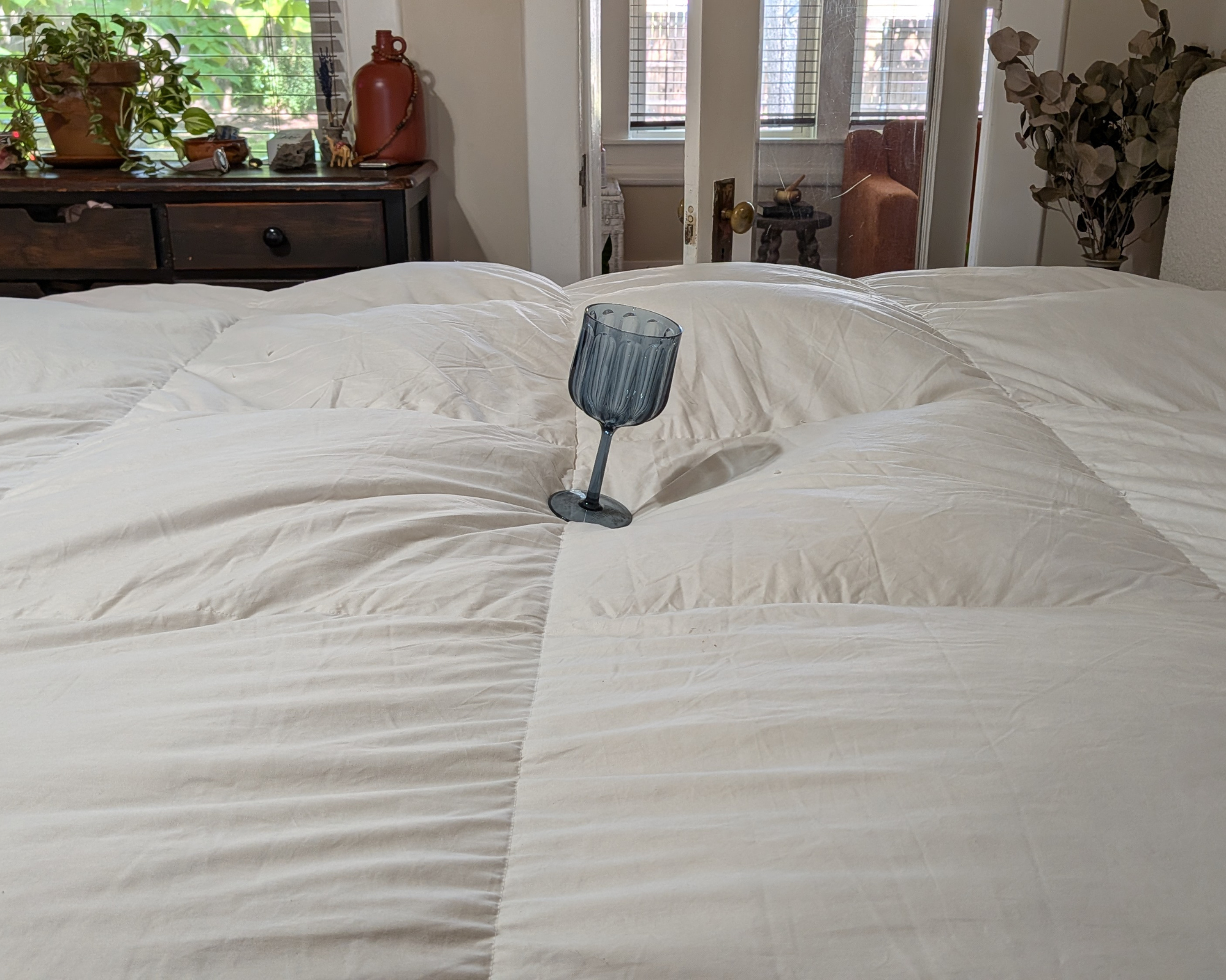 A blue cup leaning sideways on the Avocado Down Mattress Topper.