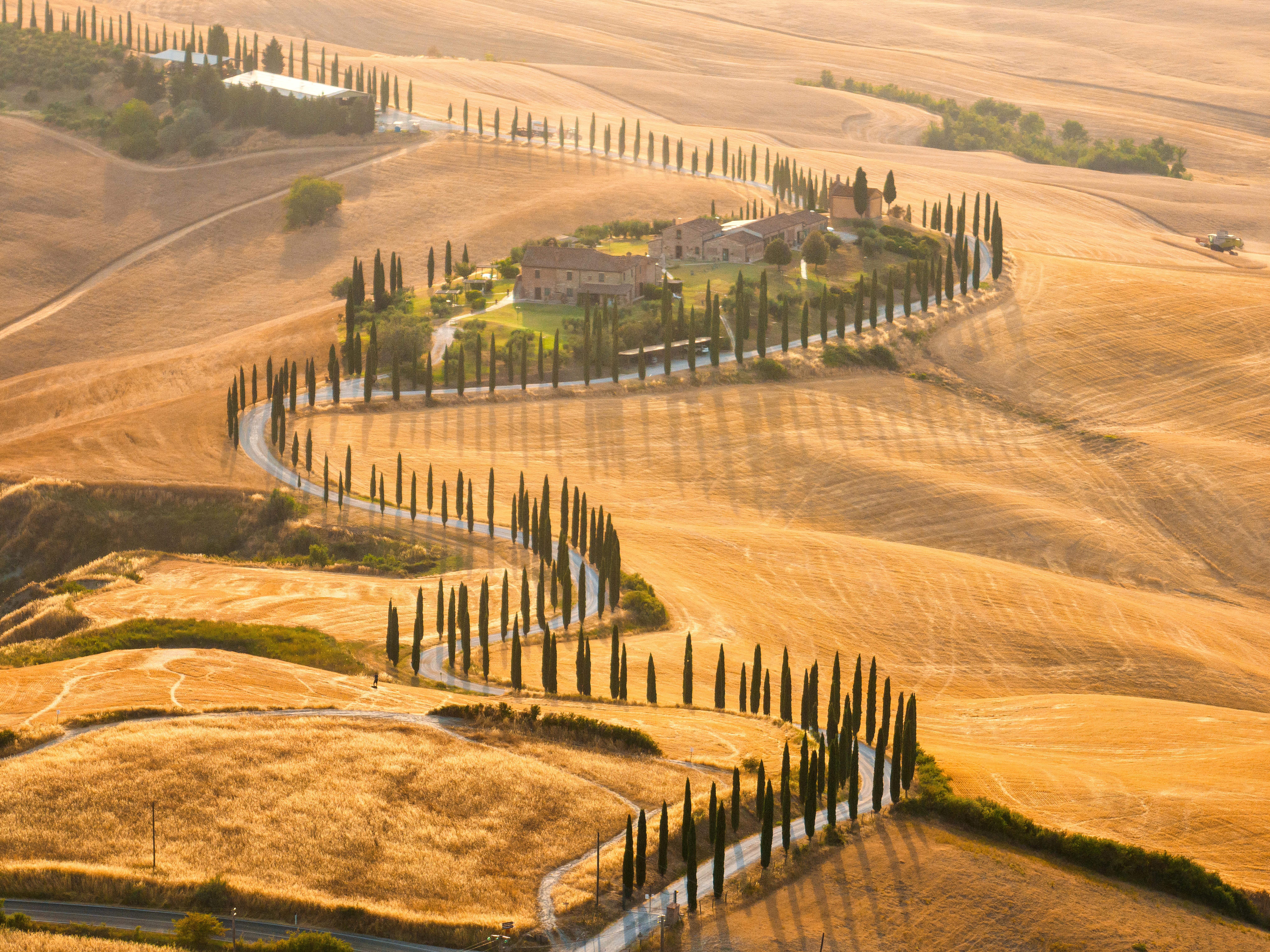 A golden-tinted sunset scene shows winding streets from above, dotted in pine trees.