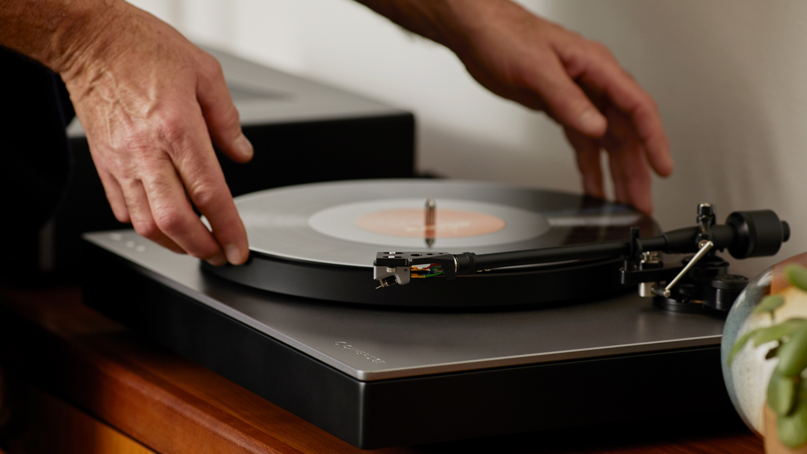 someone placing a record on the cambridge audio alva tt v2 turntable