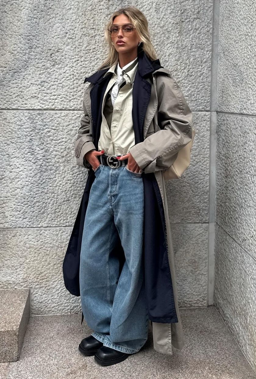 @emilisindlev wears blue baggy jeans. a trench coat, button-up shirt and square-toe Chelsea boots