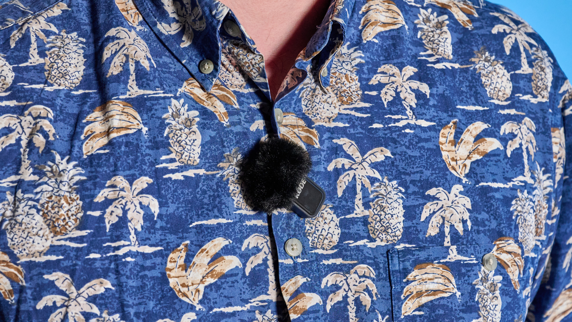 the rode wireless micro microphone with the black charging case and two black transmitter mics photographed against a blue background