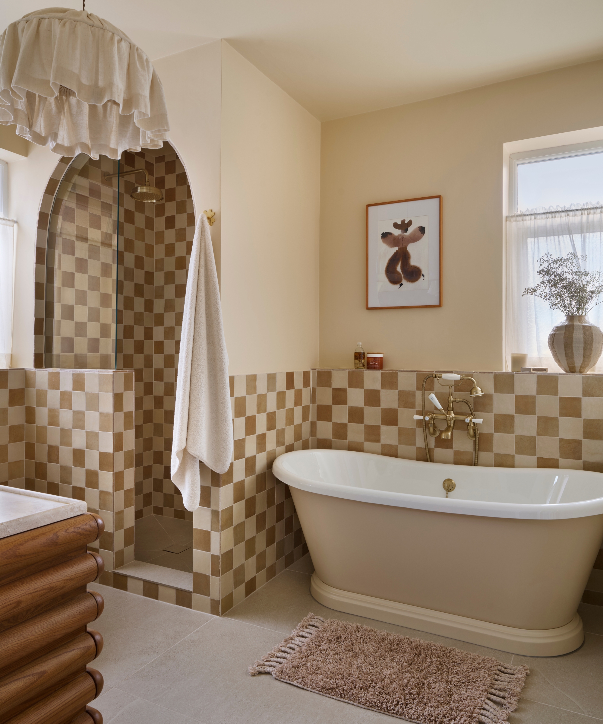 A bathroom with warm white walls, light brown and white checkerboard tiles on the lower half of the walls, and a wooden vanity