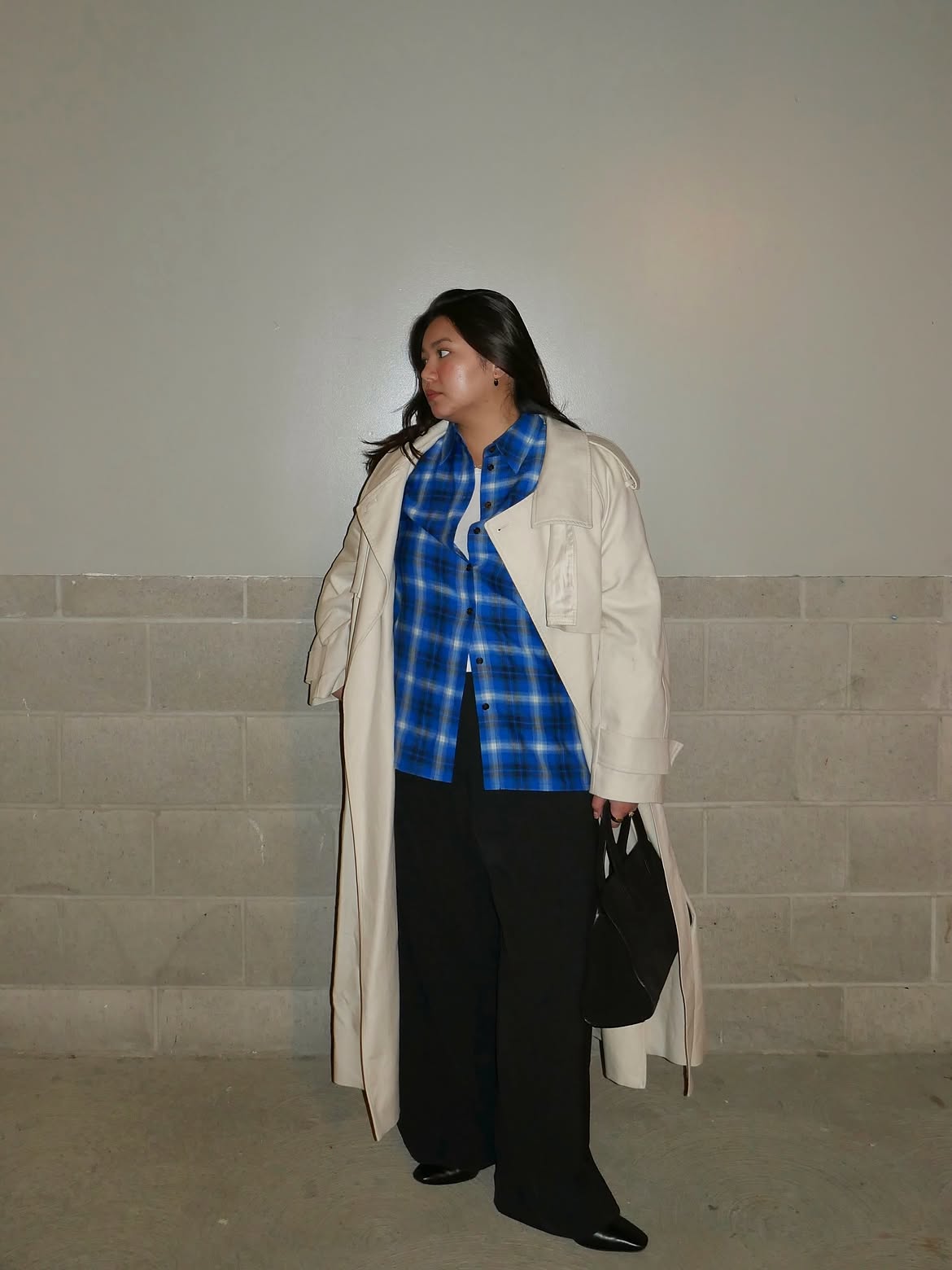 Woman wearing checked shirt in blue, a beige trench coat and utility trousers