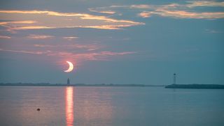 A partial solar eclipse seen during sunrise at Delaware Breakwater Lighthouse on June 10, 2021.