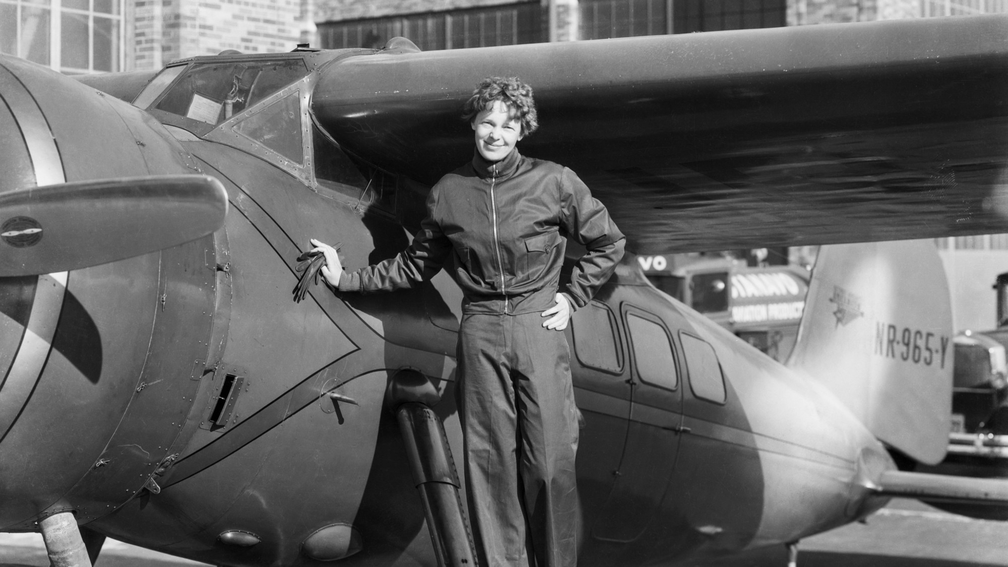 Amelia Earhart is seen with her airplane in a historic photo.