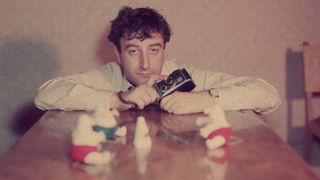 circa 1960: Comic actor Peter Sellers (1925 - 1980) holding a camera and with soft toys arranged on a table top on which he is leaning. (Photo by Hulton Archive/Getty Images)