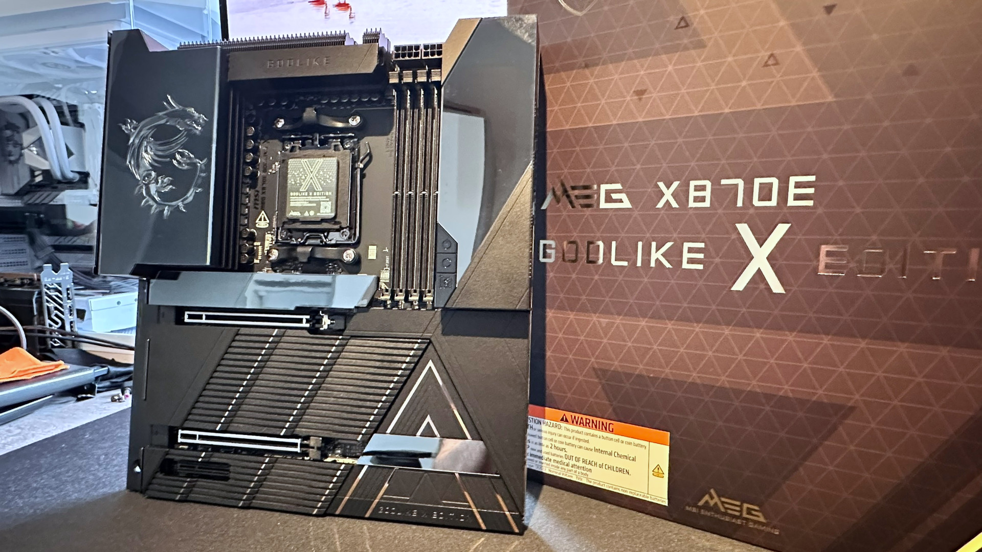 A photo of an MSI MEG X870E Godlike X Edition motherboard, next to its retail box.