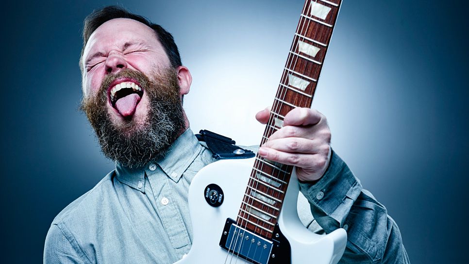 Man playing electric guitar with tongue stuck out