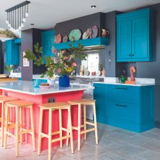 Blue shaker kitchen with black walls and pink island