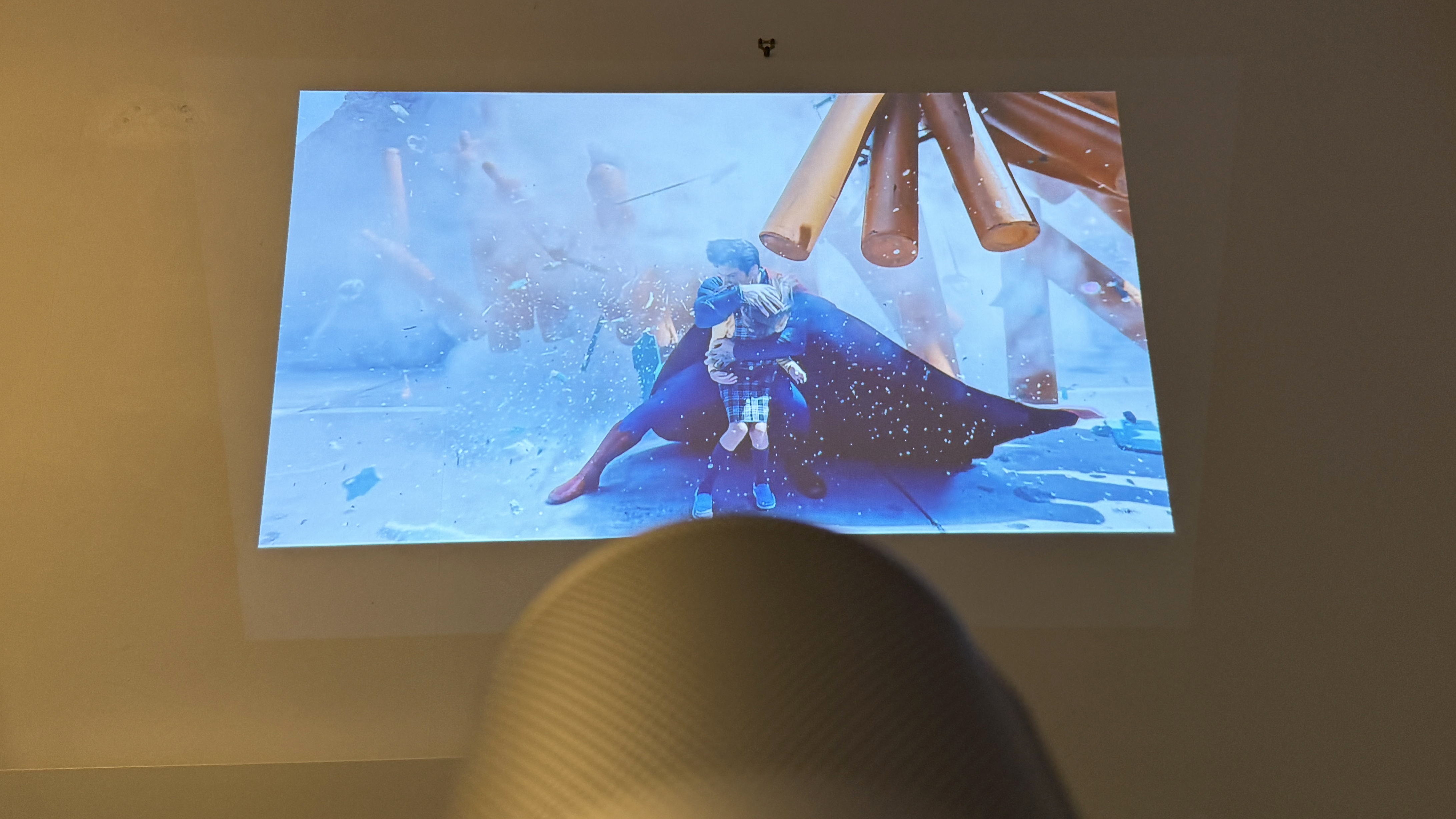 The XGIMI MoGo 4 portable projector showing an image of Superman saving a child, projected on a wall