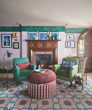 colorful sitting room with green armchairs and patterned ottoman and rug with pink walls