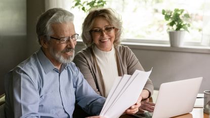 Smiling older couple looks at retirement planning documents.