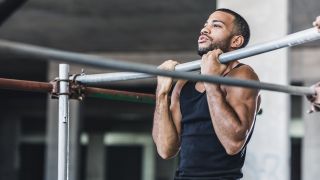 Man performs chin up in gym