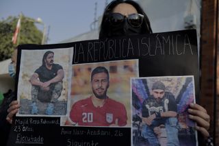 A woman protesting outside the Iranian embassy in Mexico City holds a placard featuring a photo of Amir Nasr-Azadani