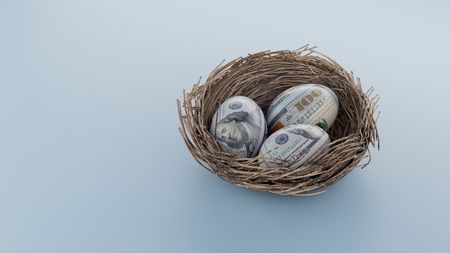 Three eggs imprinted with hundred-dollar bills in a nest.