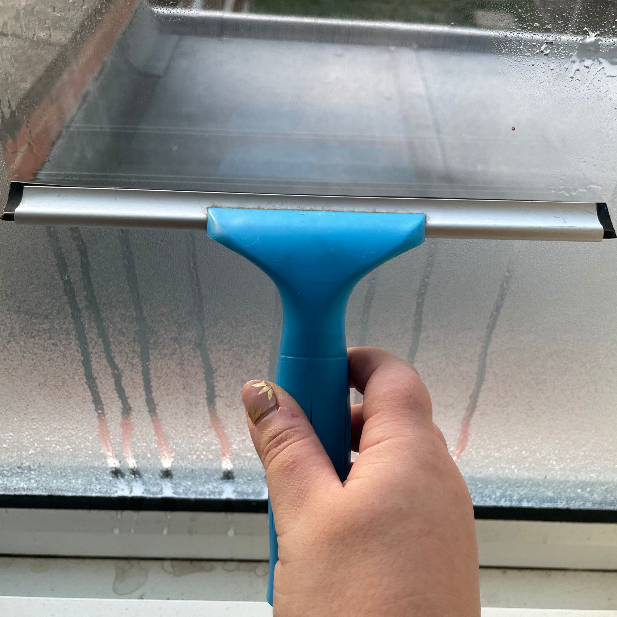 Blue squeegee removing condensation from window