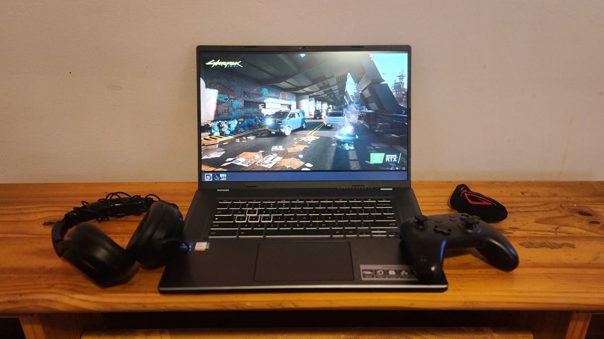 The Acer Chromebook 516 GE facing forward on a desk with gaming accessories like a gamepad and headset. The Chromebook display is showing Cyberpunk 2077 gameplay.