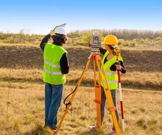 man and woman wearing yellow hi vis and hard hats stood surveying the landscape