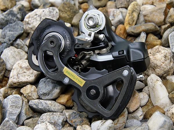 As with the mechanical version, the 7970 rear derailleur will use a carbon pulley cage. The mechanical spring only serves to minimize the slop inherent to a geared stepper motor design.