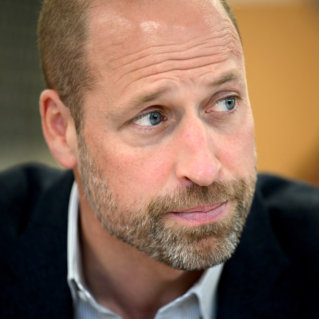 Prince William has a beard and is wearing a suit jacket and shirt