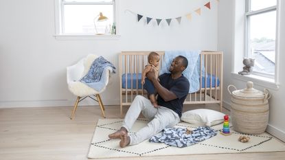 Boys nursery ideas by Brooklinen with cream chair, rug, baby and father